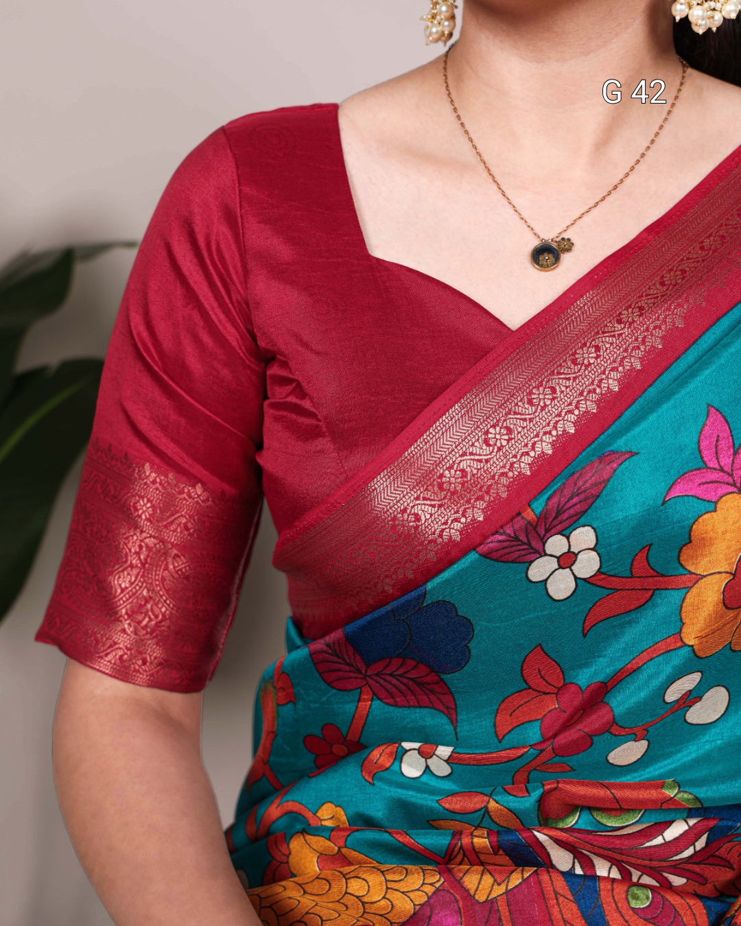 Woman wearing a colorful saree with a red blouse against a neutral background