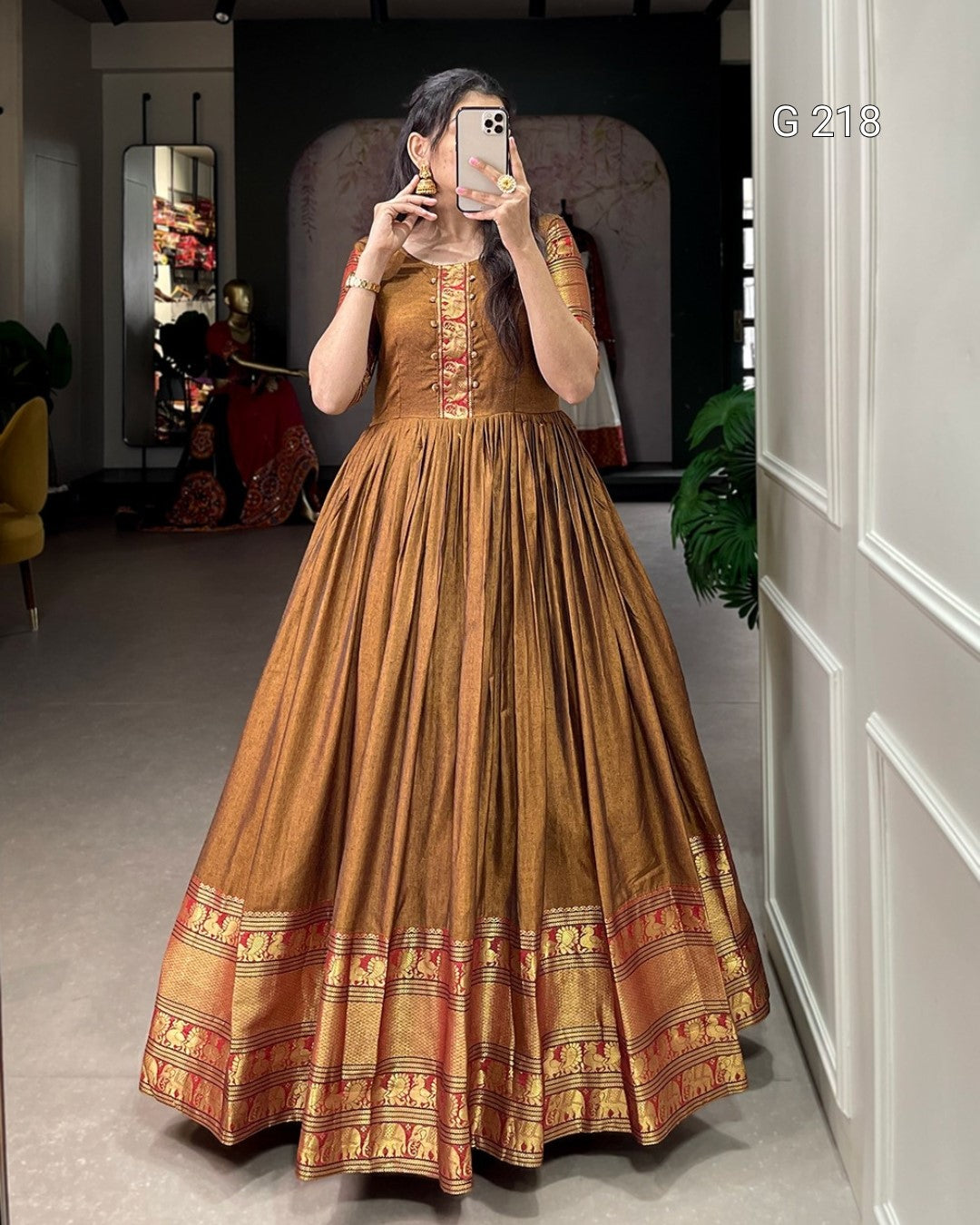 Woman wearing a traditional brown and gold dress in a room with decor elements.