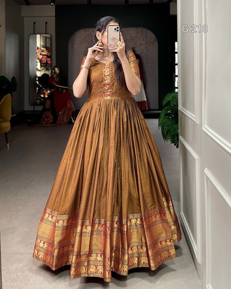 Woman wearing a traditional brown and gold dress in a room with decor elements.