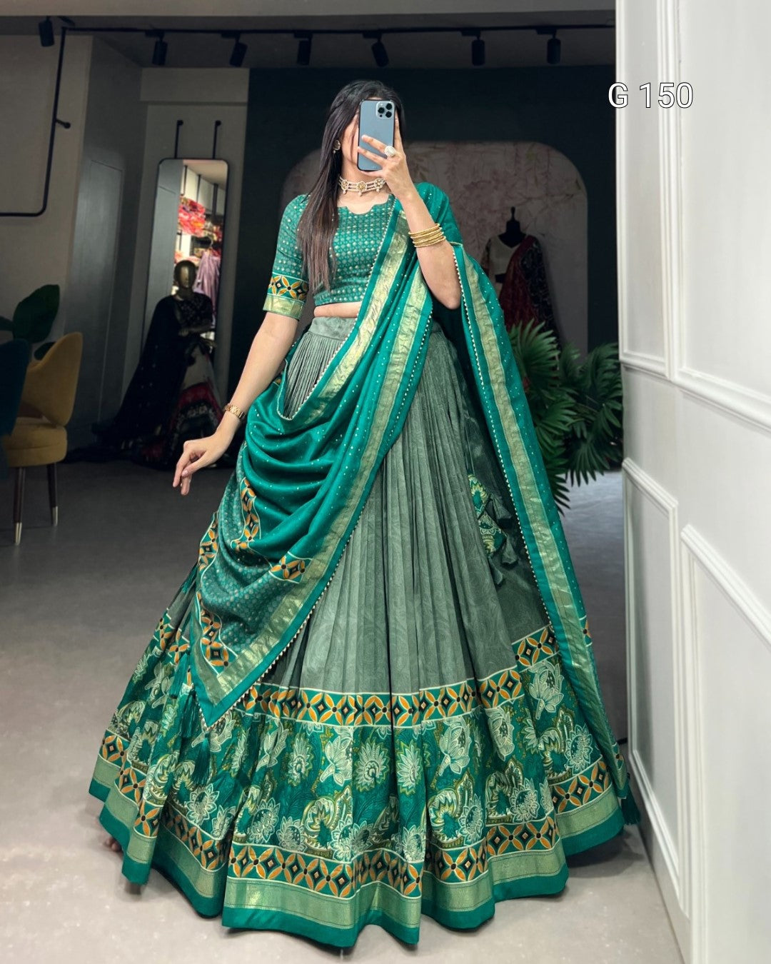 Woman wearing a green traditional outfit with a matching dupatta in a room.