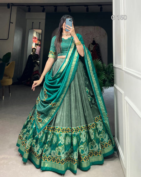 Woman wearing a green traditional outfit with a matching dupatta in a room.