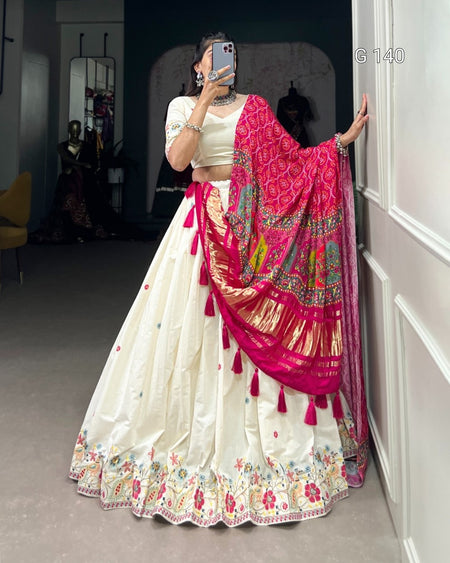 Person wearing a traditional outfit with a white and pink saree in a room.