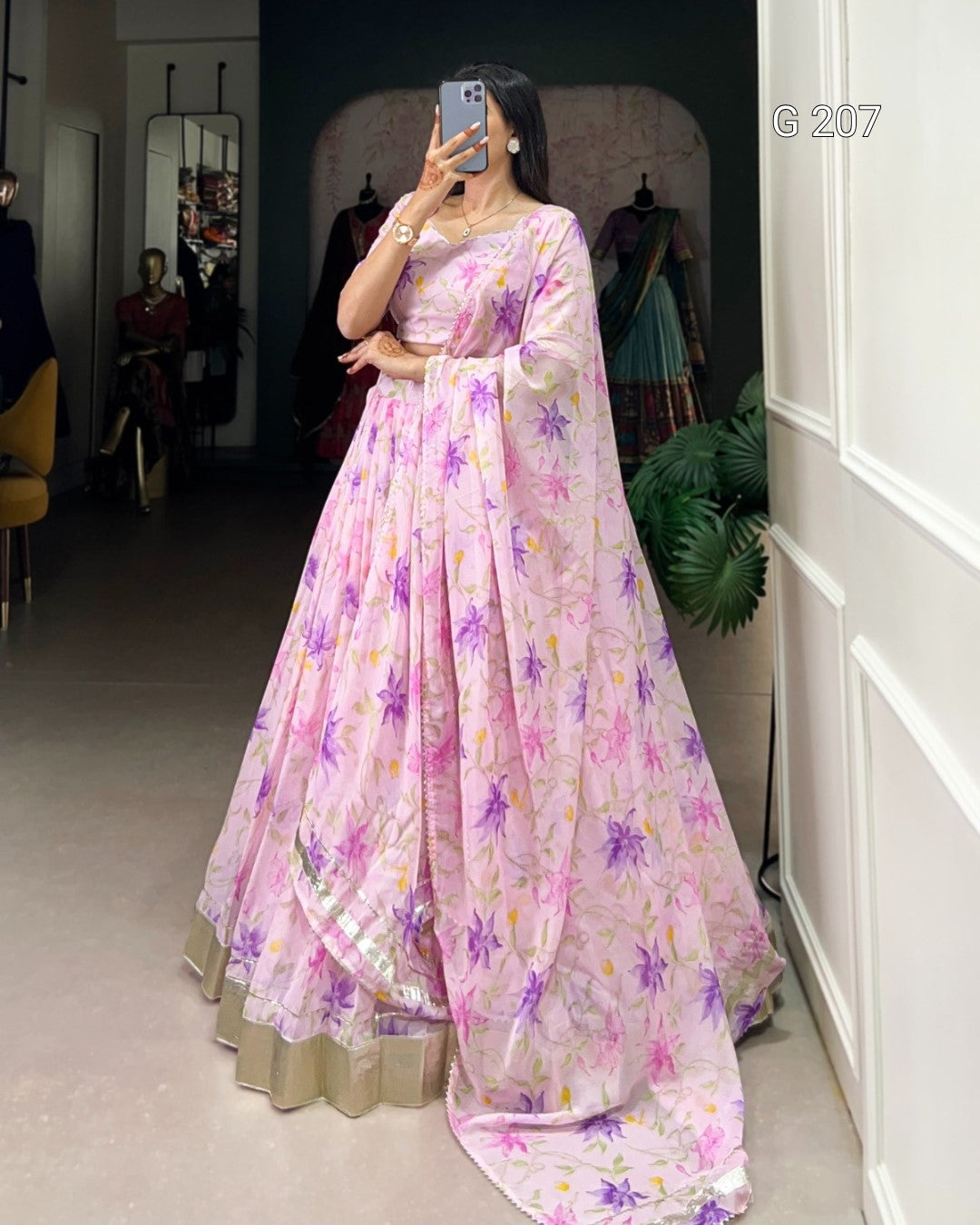 Person wearing a pink floral saree in a room with a mirror and chair.
