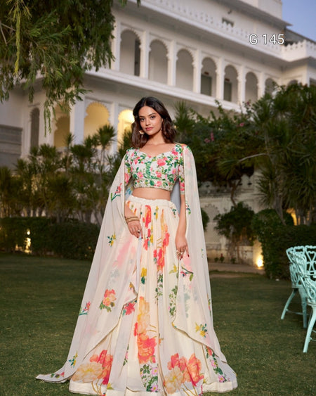 Woman in a floral outfit standing outdoors with a building and greenery in the background