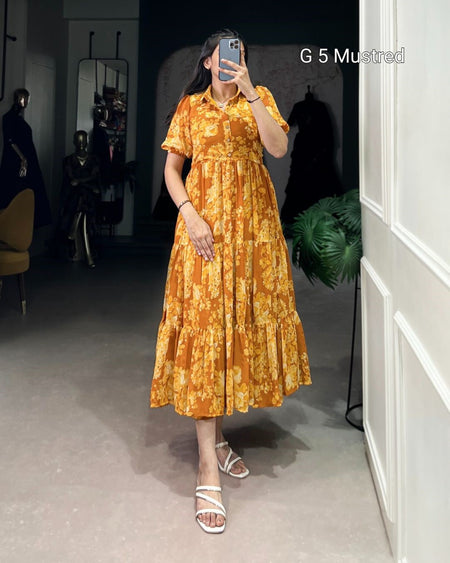 Woman taking a mirror selfie wearing an orange floral dress in a room with white walls and a plant.
