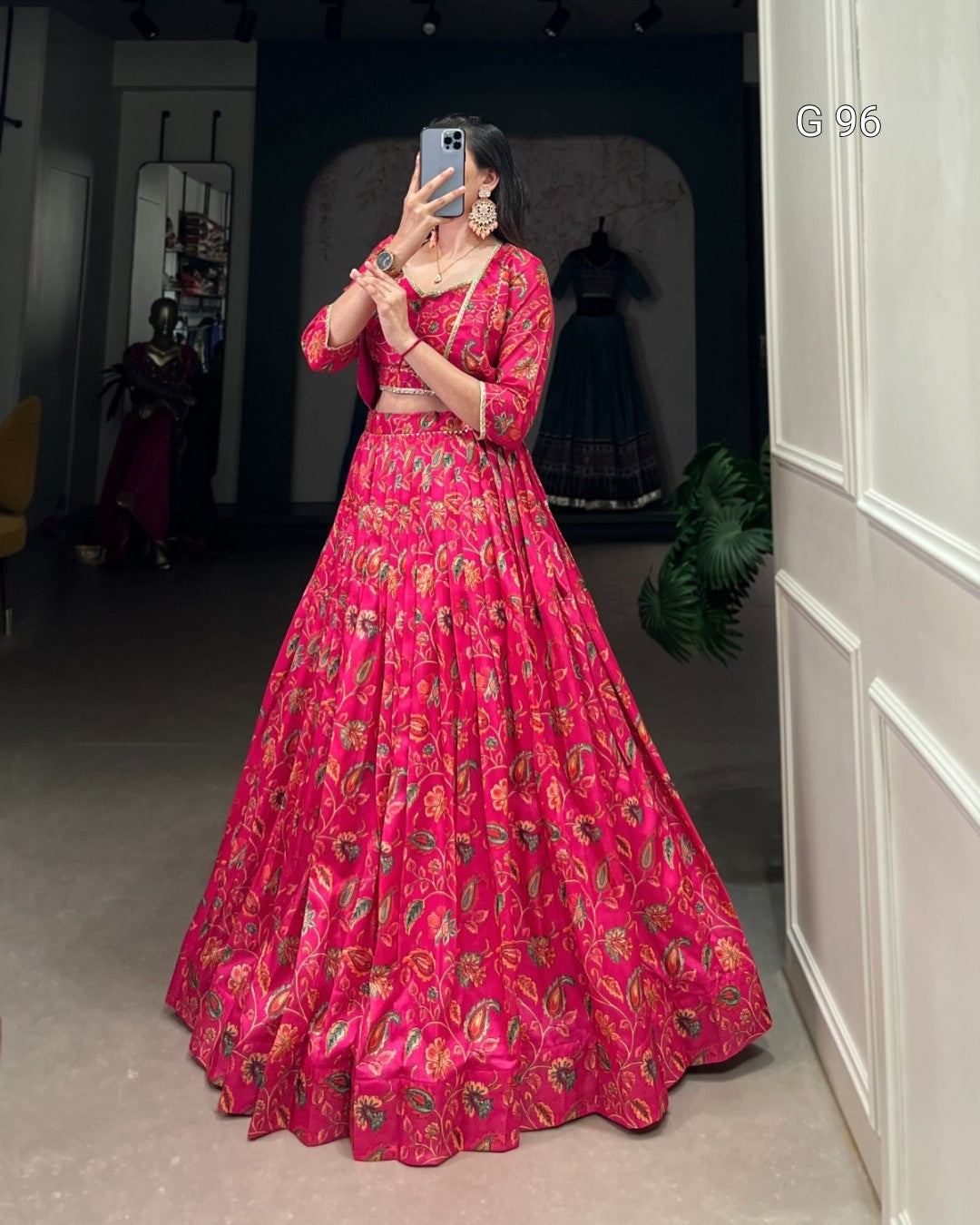 Person wearing a bright pink traditional outfit with floral patterns in a room.