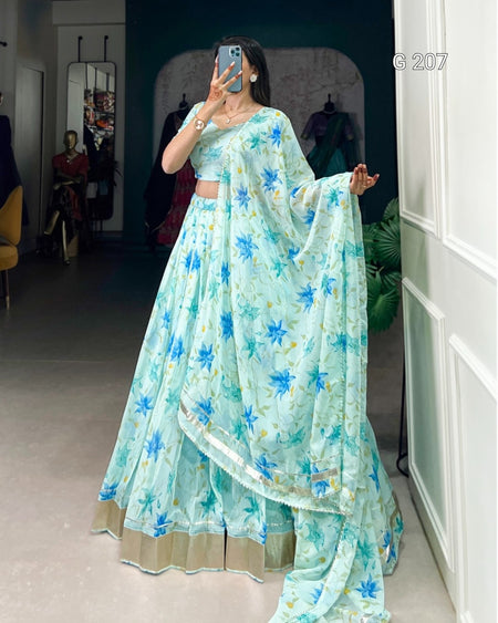 Person wearing a light blue floral saree in a room.