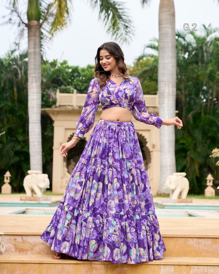 Woman in a purple floral outfit standing in front of a fountain with palm trees in the background