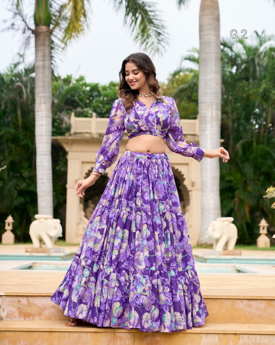 Woman in a purple floral outfit standing in front of a fountain with palm trees in the background