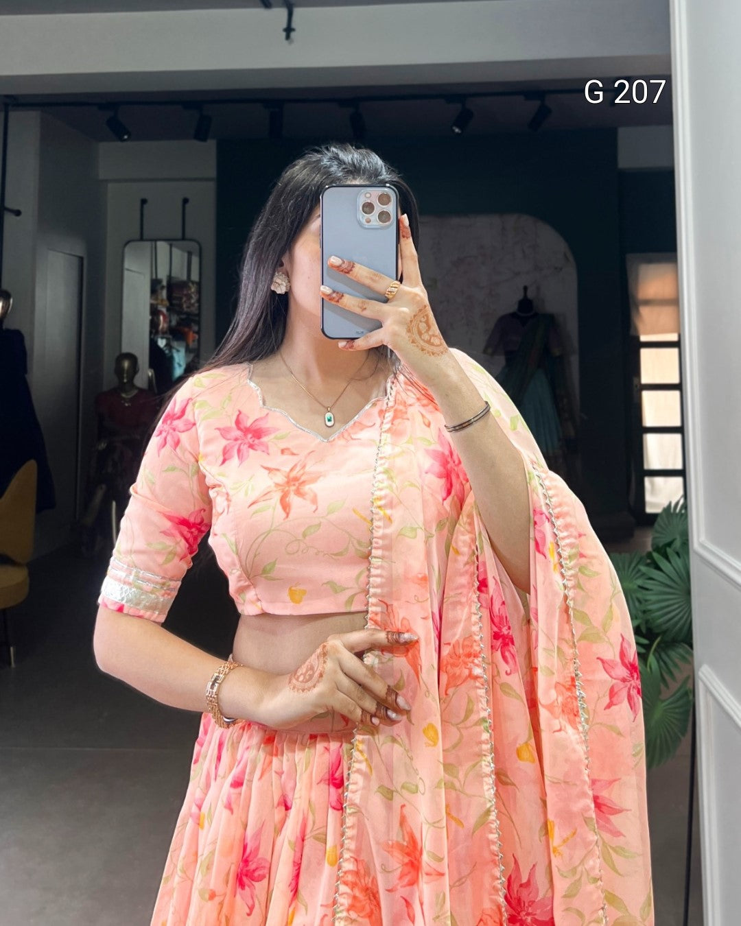 Woman taking a mirror selfie wearing a floral pink saree.