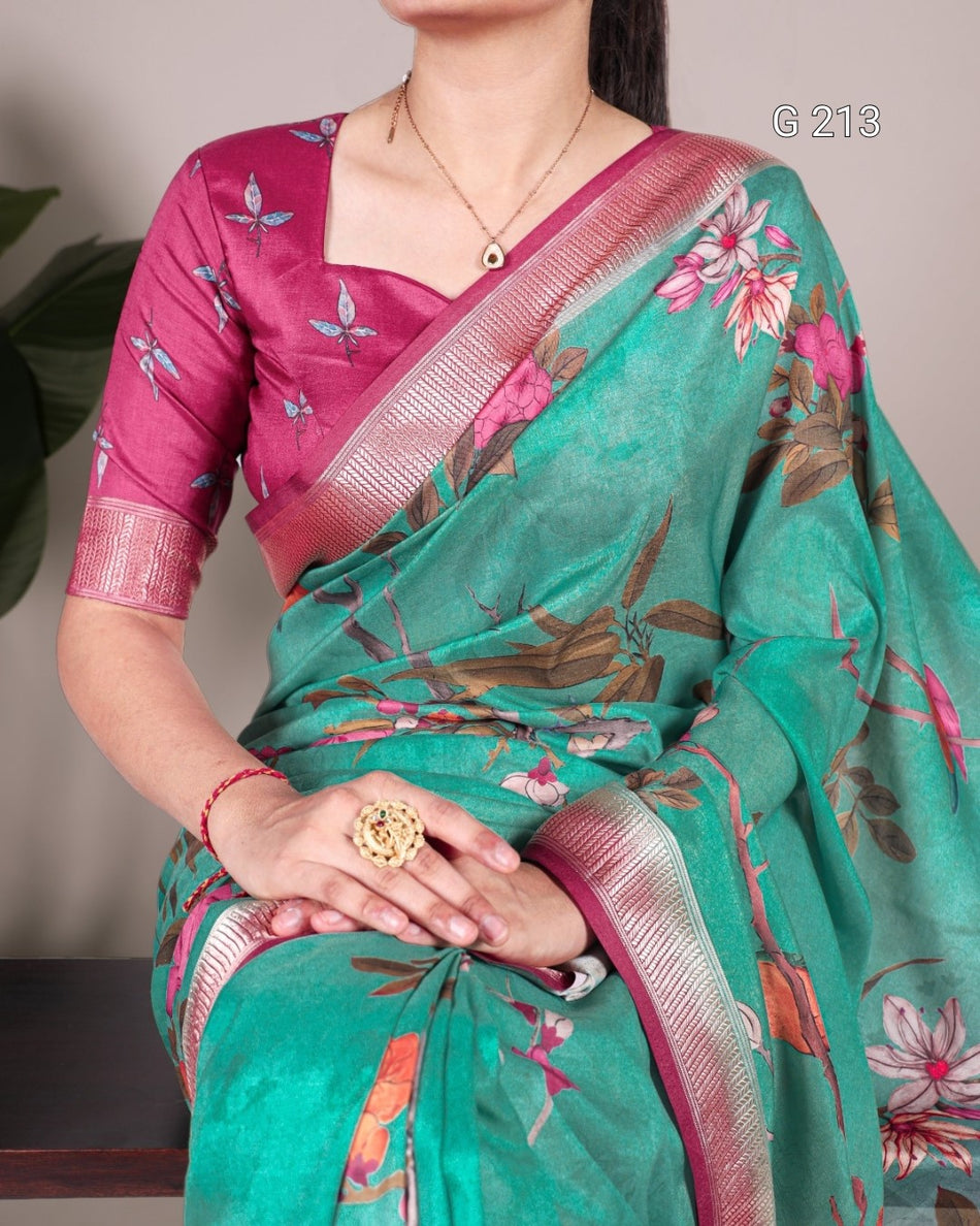 Woman wearing a green floral saree with a pink blouse, holding a ring.