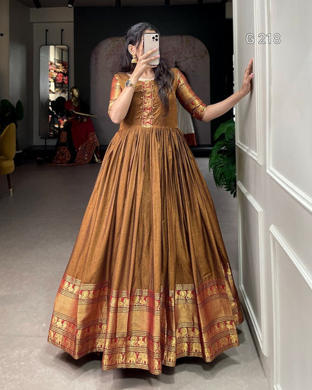 Woman taking a mirror selfie wearing a traditional brown and gold dress.