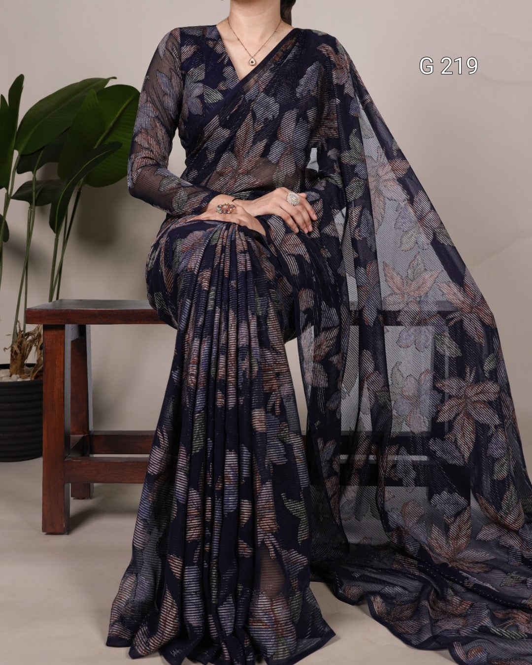 Woman wearing a dark floral saree with a plain background