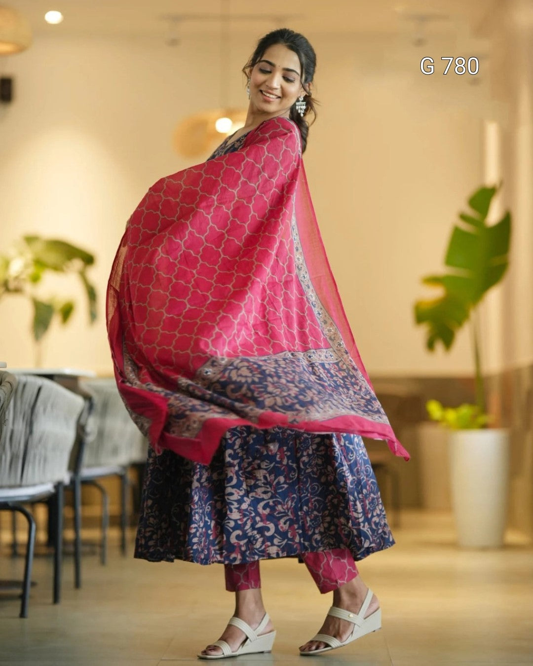 Woman in a pink and blue traditional outfit with a patterned dupatta in an indoor setting.