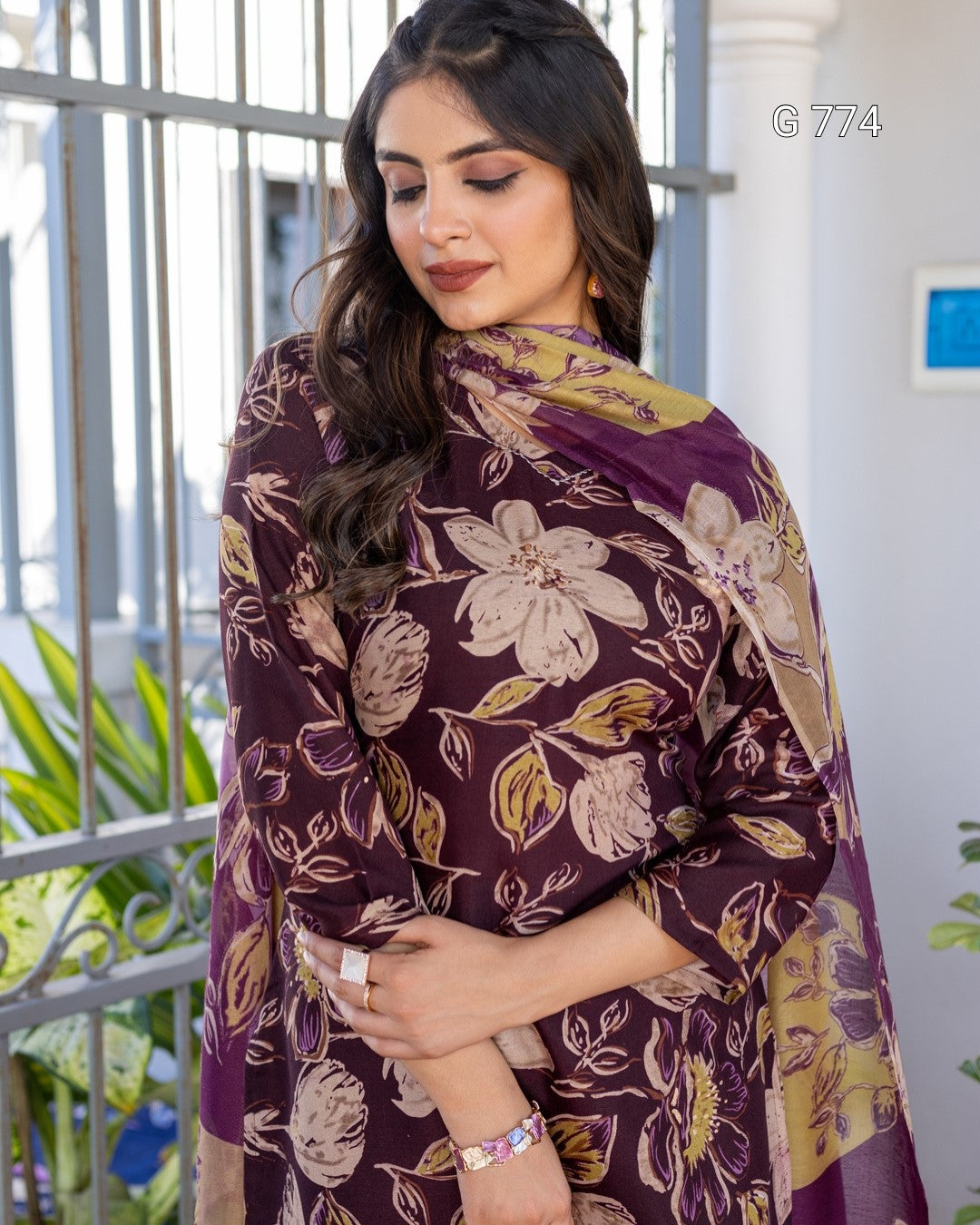 Woman wearing a floral-patterned purple dress with a matching shawl outdoors.