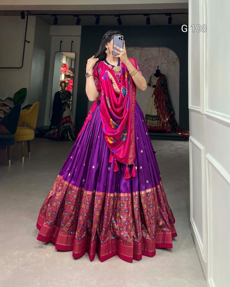 Person wearing a vibrant purple and pink traditional outfit with a colorful dupatta in a room.