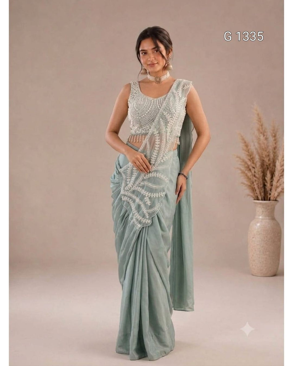 Elegant mint green saree featuring intricate white embroidery and a matching sleeveless blouse.
The saree is styled with traditional jewelry for a graceful and sophisticated look.