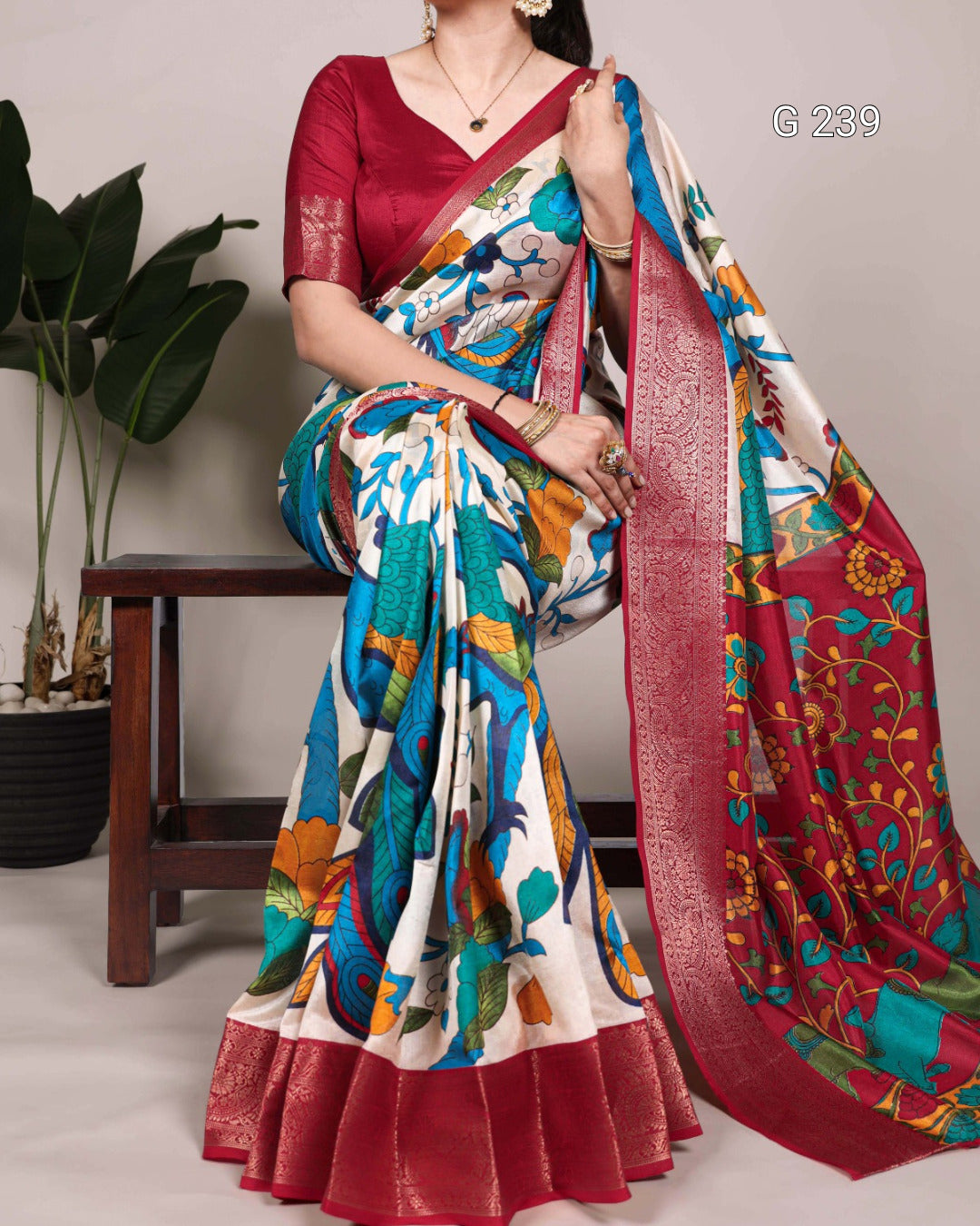 Woman wearing a colorful saree with a red border, standing against a neutral background.