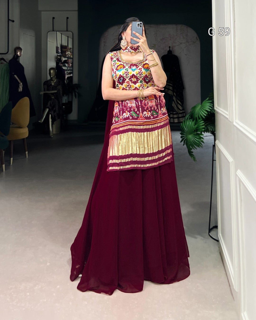 Person wearing a colorful top and maroon skirt in a room with a mirror.