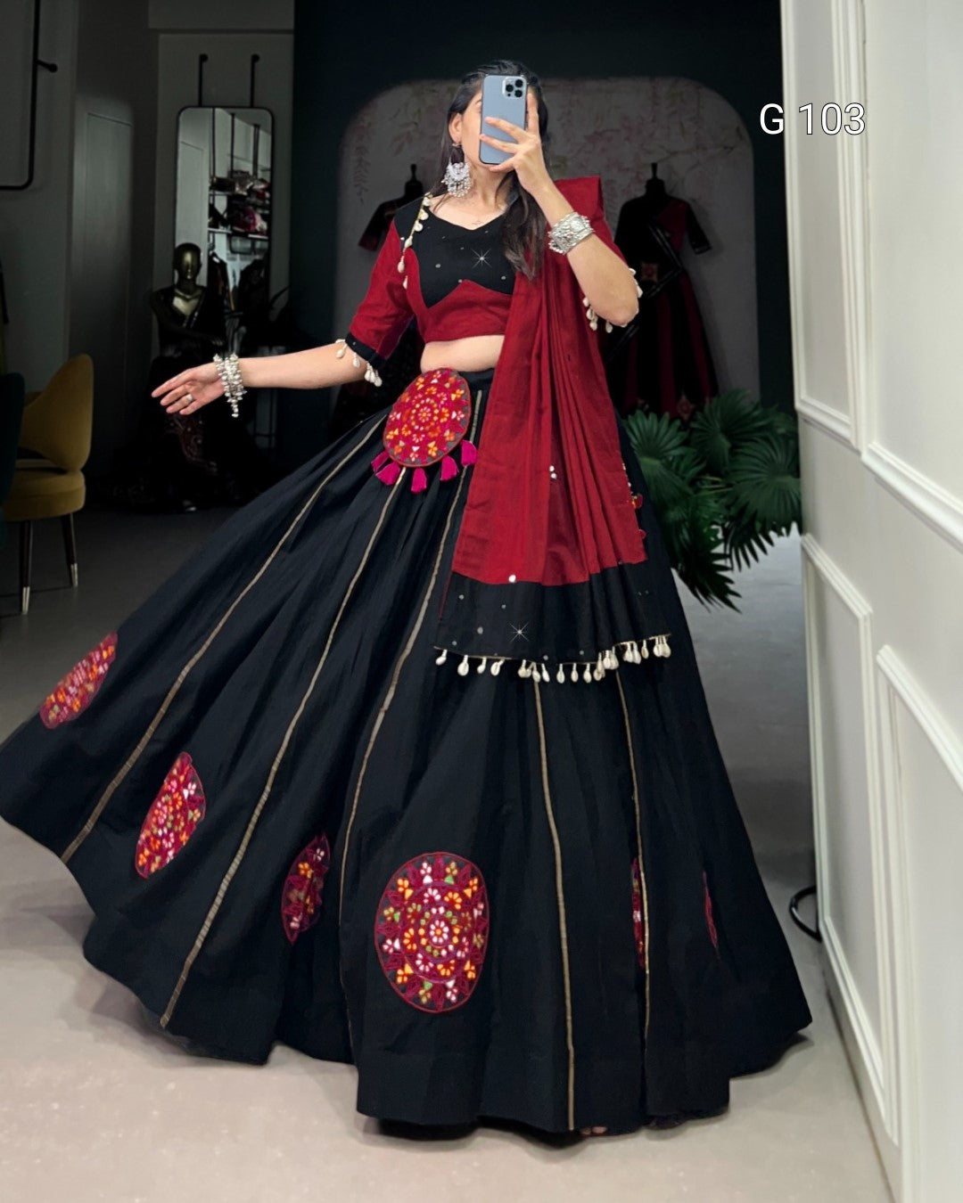 Person wearing a black and red traditional outfit with floral patterns in a room.