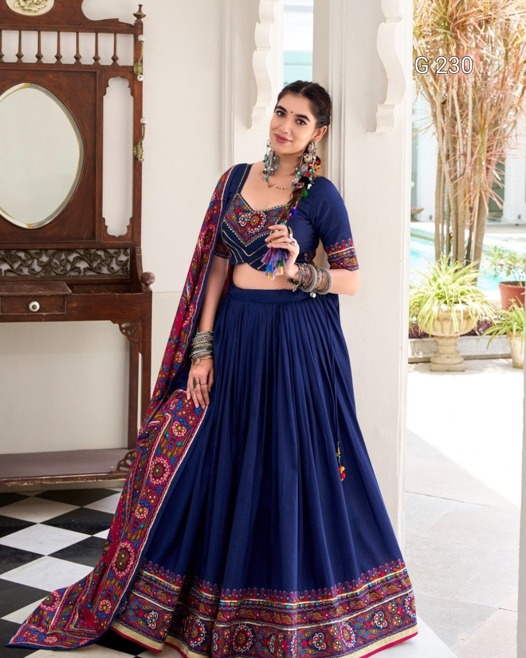 Woman wearing a traditional blue saree with a colorful border indoors.