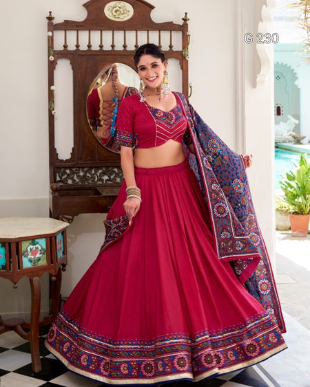 Woman in a red traditional outfit with a patterned dupatta in a decorated room.