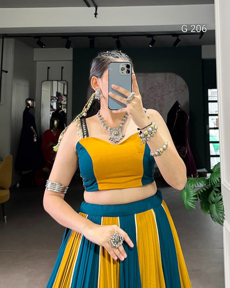 Person wearing a traditional outfit with a yellow and blue top and skirt, taking a mirror selfie.