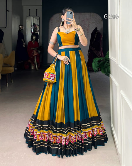 Woman wearing a traditional outfit with a yellow and blue dress, standing in a room.
