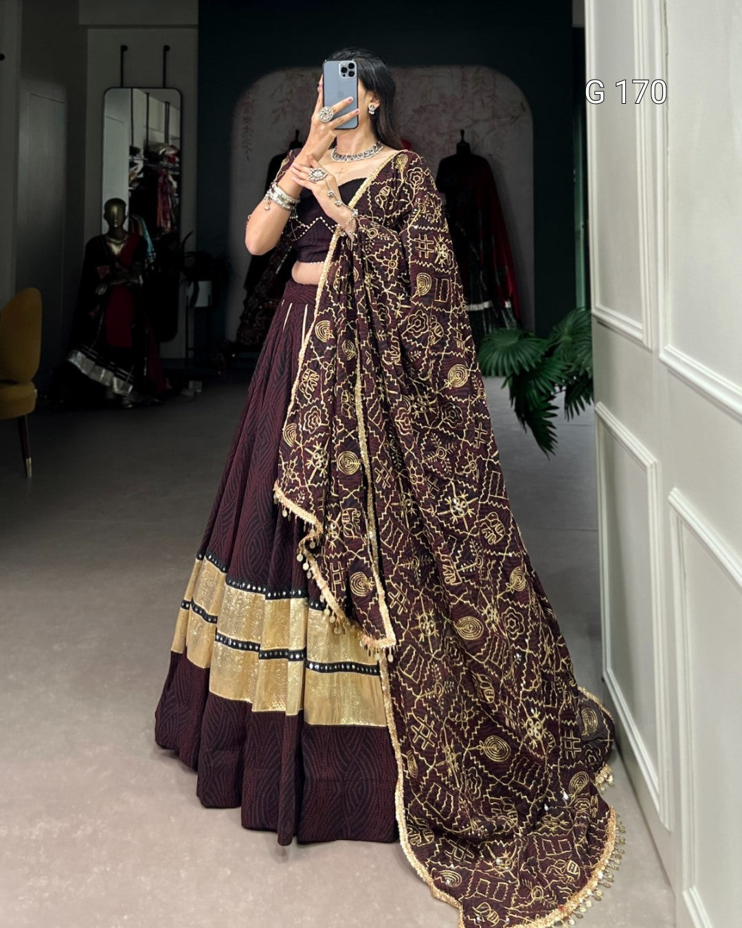 Person wearing a traditional outfit with a patterned dupatta in a room.