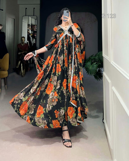 Woman in a floral dress taking a mirror selfie in a room with a white wall and plant.