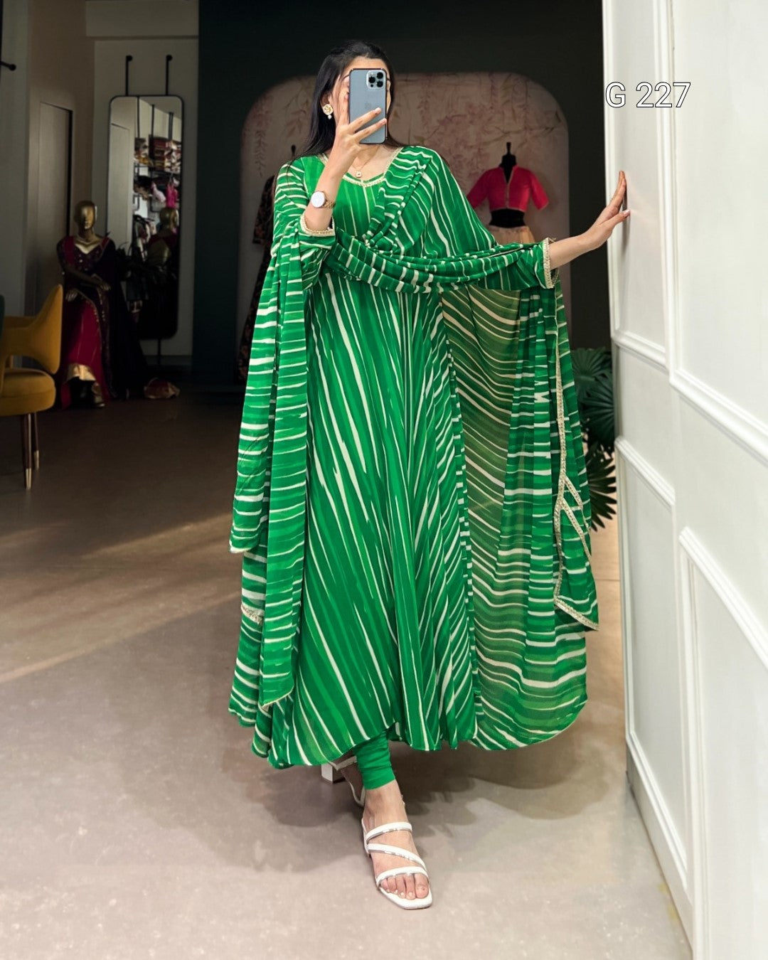 Person wearing a green and white striped dress taking a mirror selfie.