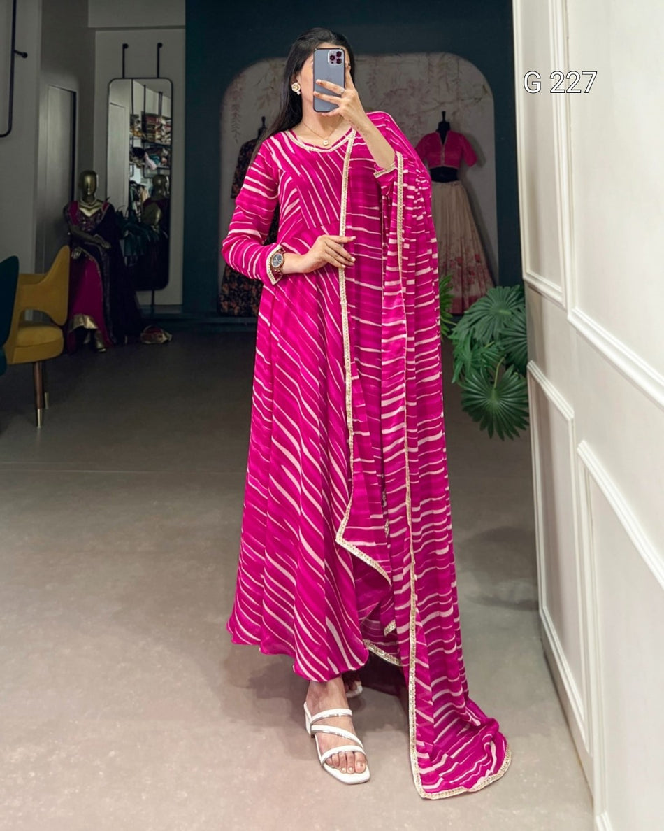 Person wearing a bright pink traditional outfit with white patterns in a room.