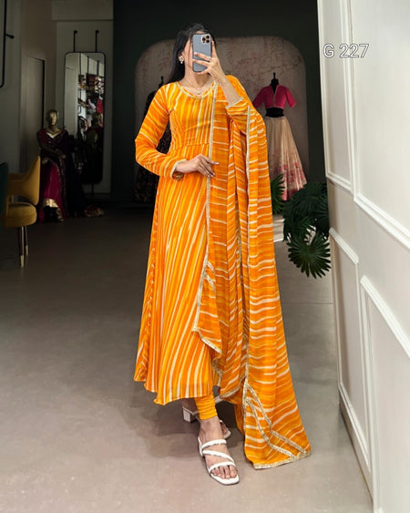 Woman taking a mirror selfie wearing an orange and yellow patterned dress in a room.