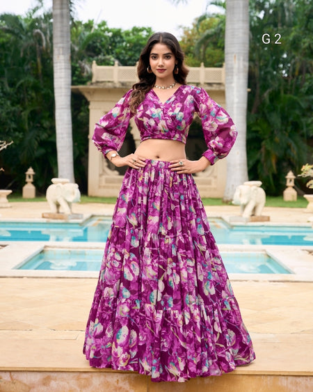 Woman in a purple floral outfit standing by a pool with greenery in the background
