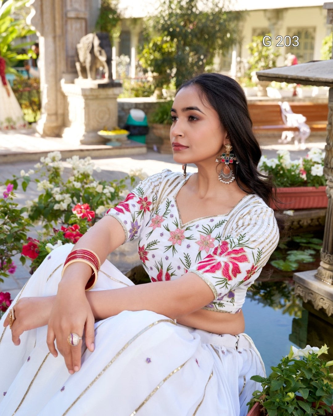 Woman in a floral blouse sitting by a pool with decorative elements