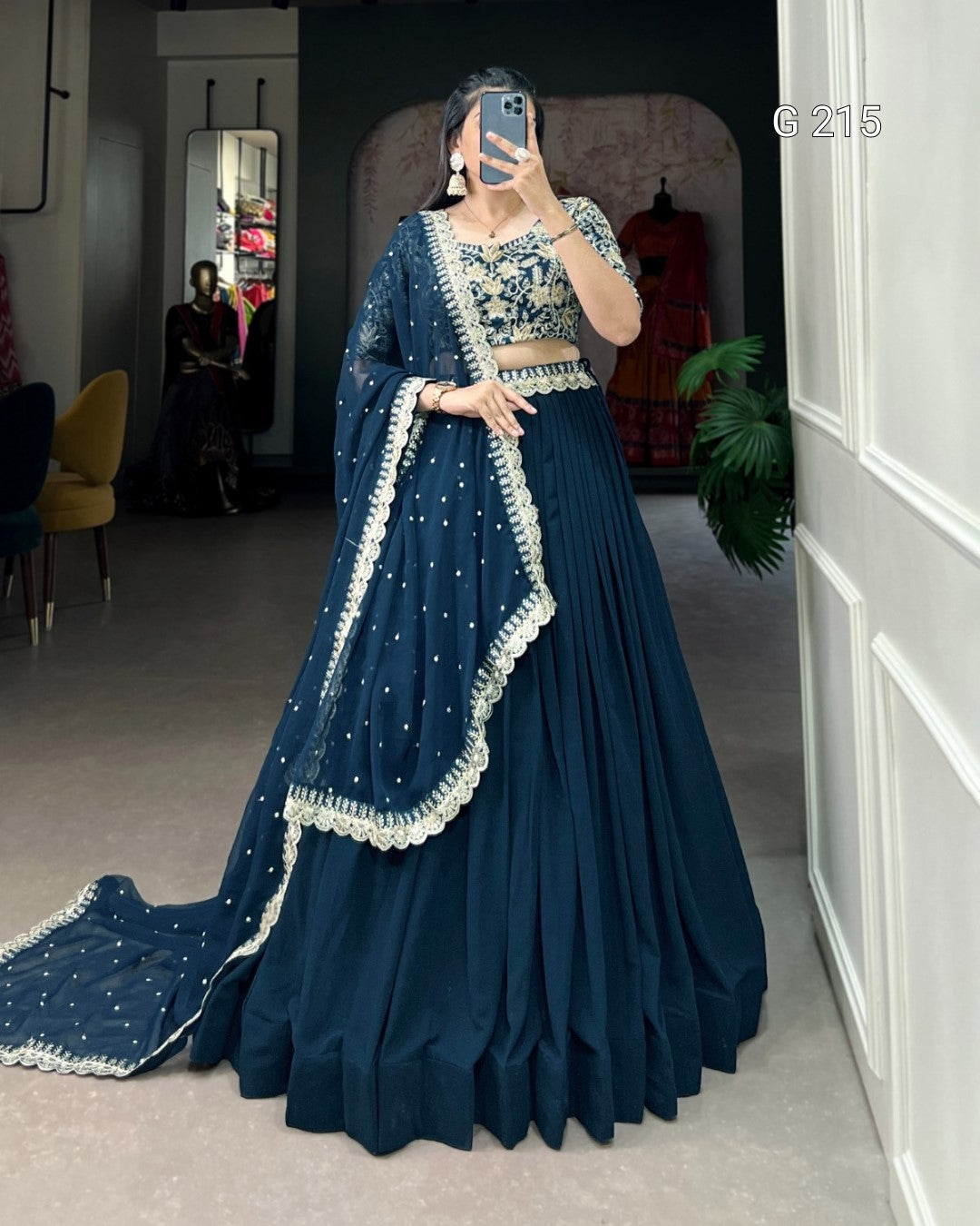 Woman wearing a traditional blue outfit with white embroidery in an indoor setting.
