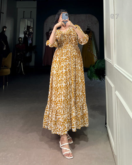 Woman taking a mirror selfie wearing a gold and white patterned dress in a room.