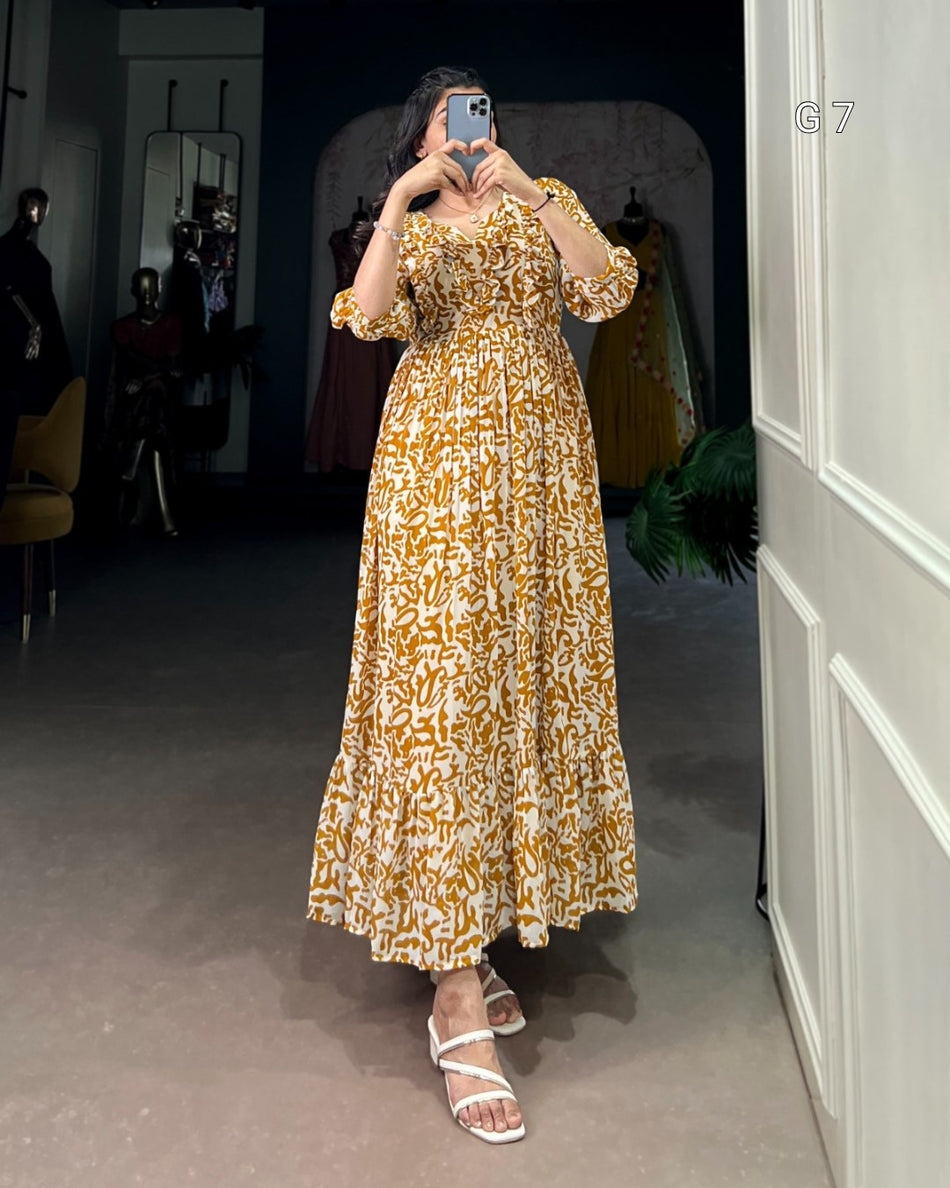 Woman taking a mirror selfie wearing a gold and white patterned dress in a room.
