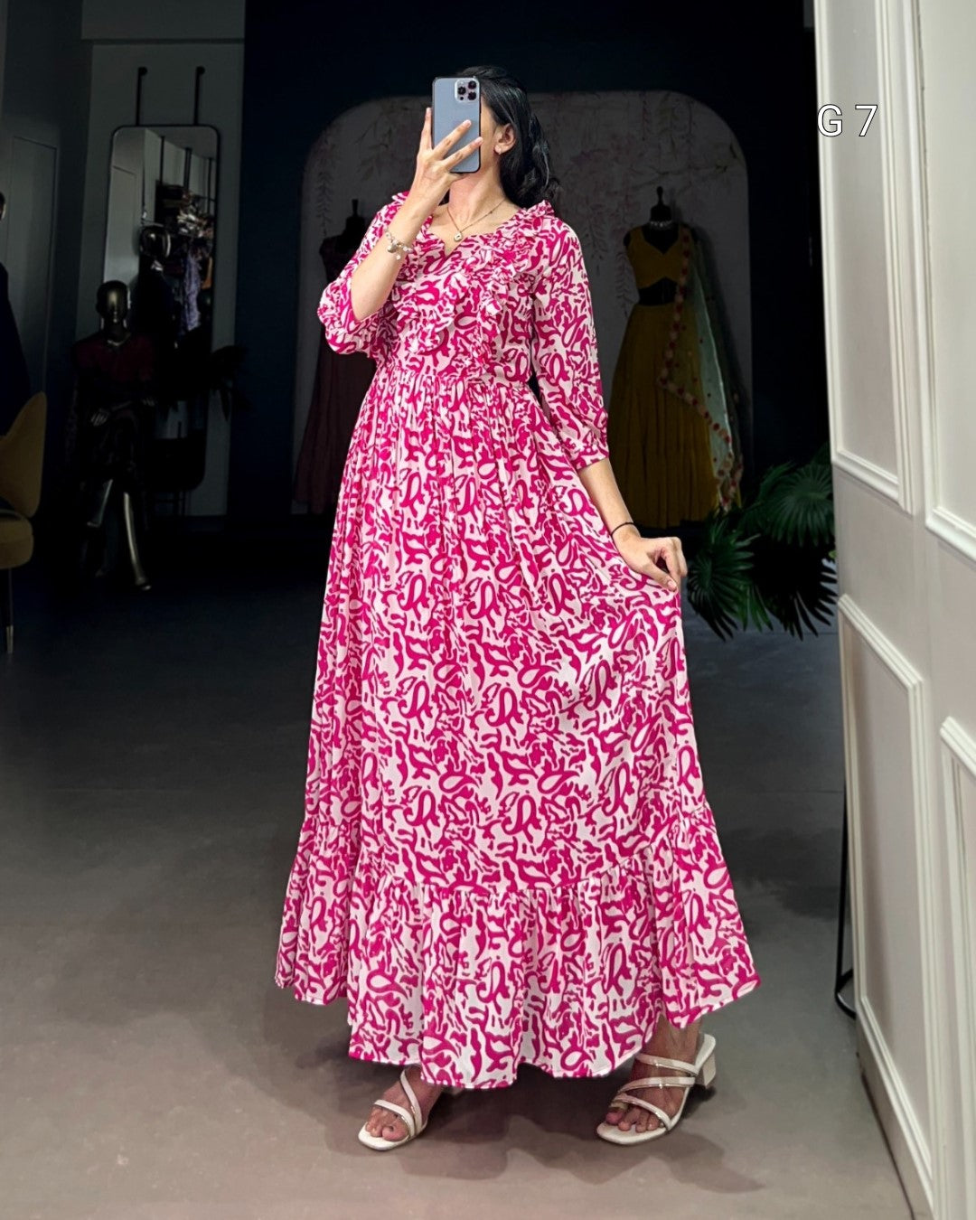 Person wearing a pink and white patterned dress standing in a room.