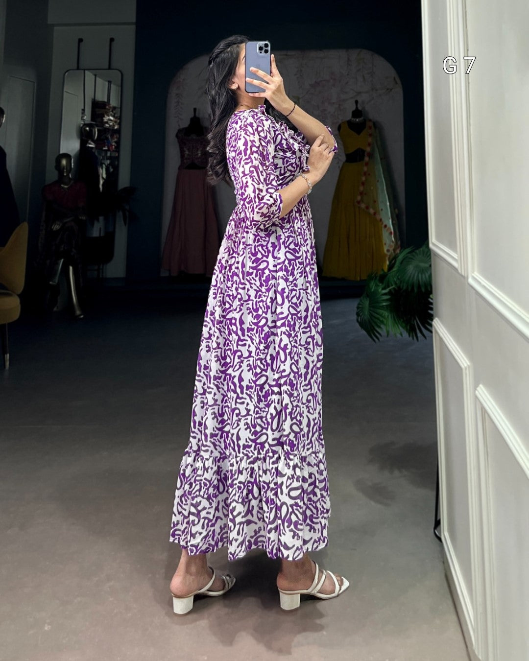 Person wearing a purple patterned dress in a fitting room.