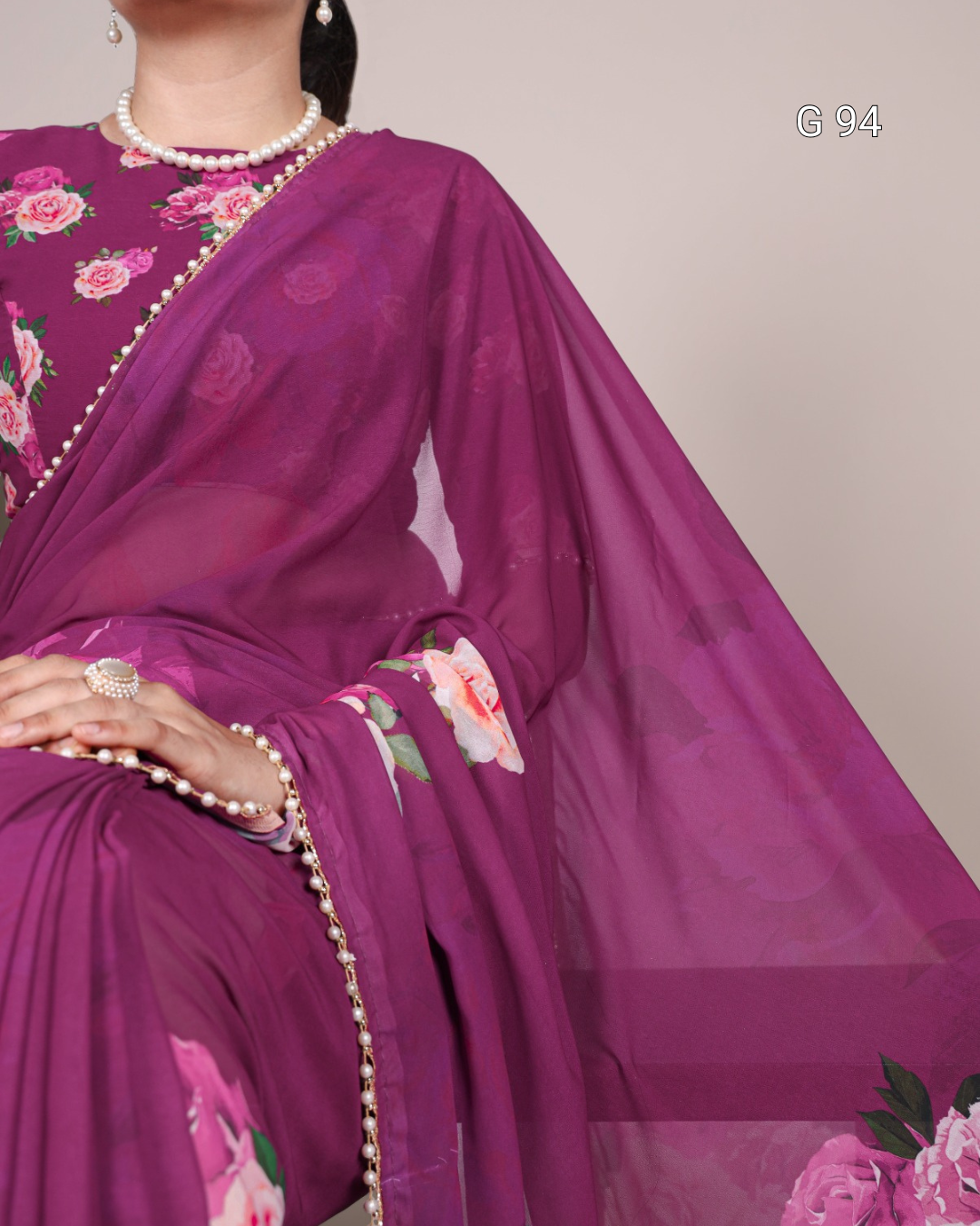Purple saree with floral patterns and a pearl necklace on a neutral background