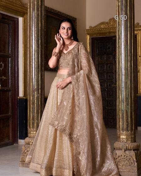 Woman in a traditional beige embroidered outfit standing in an ornate room.