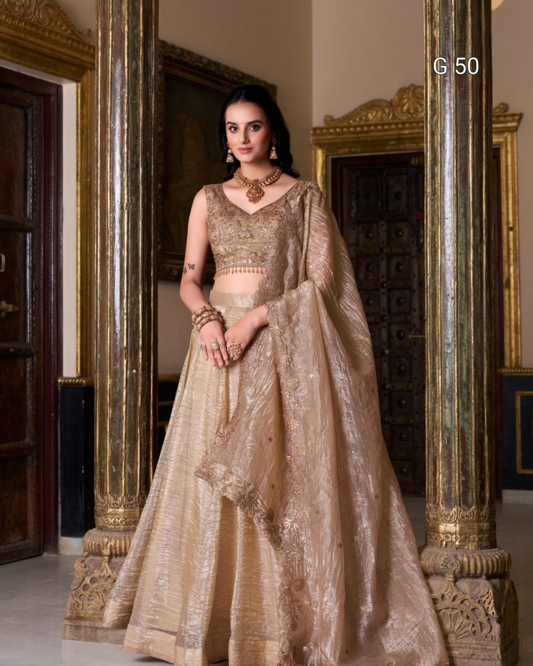 Woman in a traditional beige embroidered outfit standing in an ornate room.