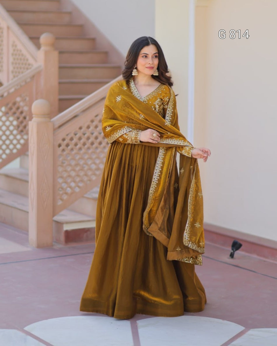 Woman in a mustard yellow traditional outfit standing in front of a staircase.
