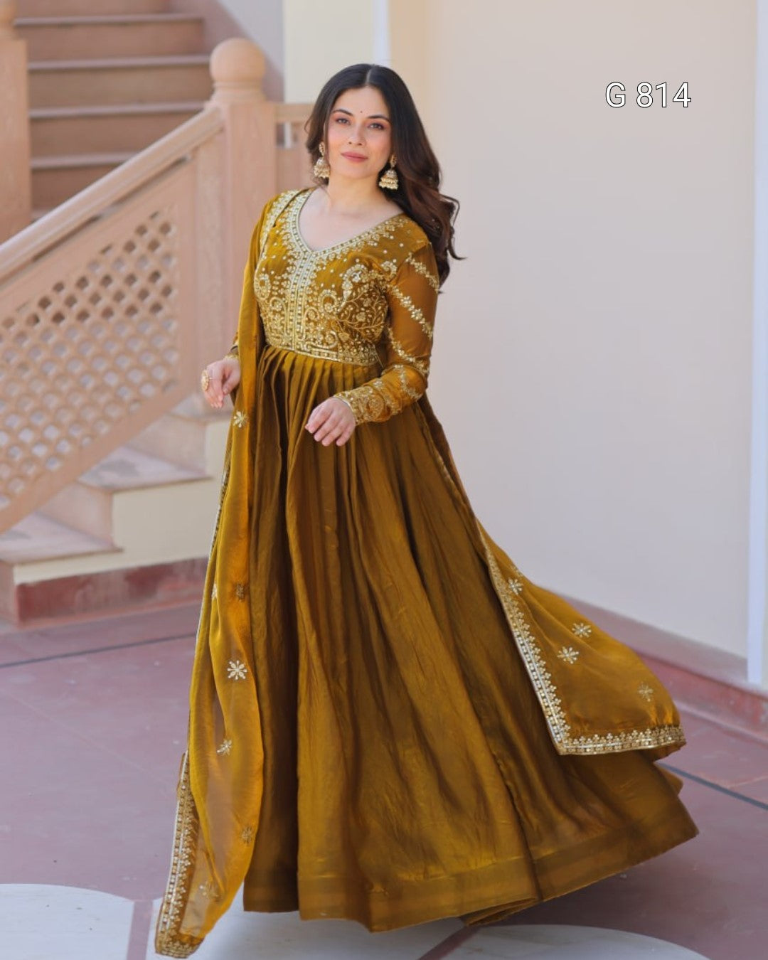 Woman wearing a mustard yellow traditional outfit with intricate designs indoors.