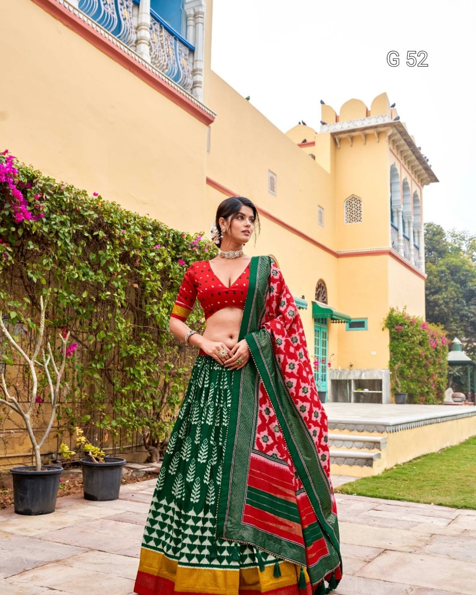 Woman in a traditional outfit standing in front of a colorful building with greenery.