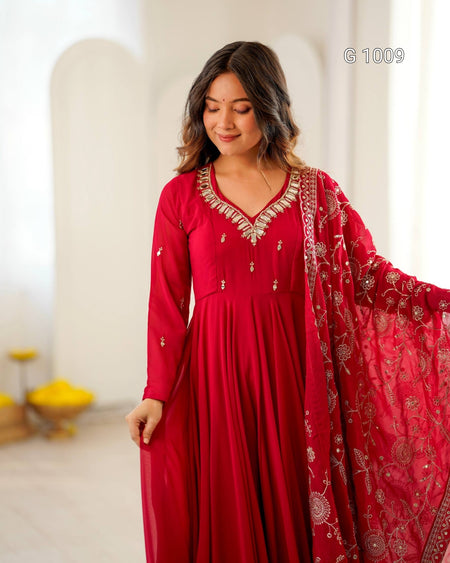 A woman wearing a red long-sleeve kurta with ornate gold embroidery around the neckline and matching red embroidered dupatta, standing in a bright indoor setting.