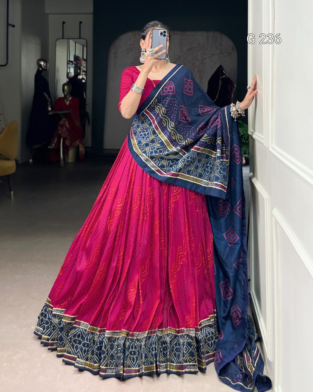 Person wearing a pink and blue traditional outfit in a room.