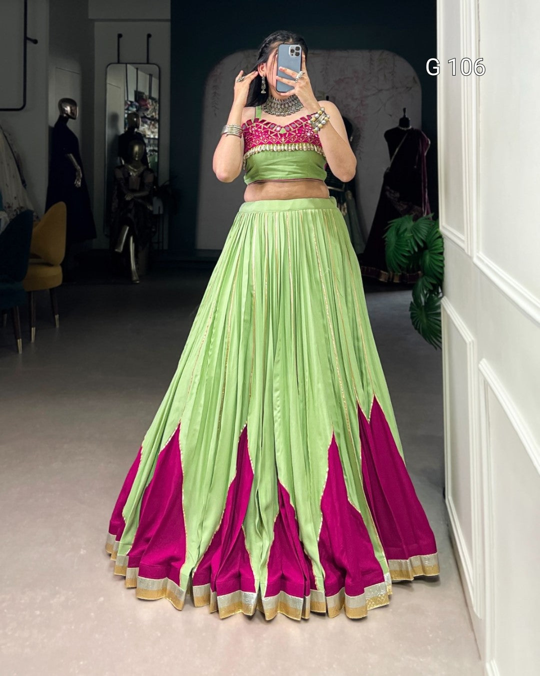 Person wearing a green and pink traditional outfit in a room.
