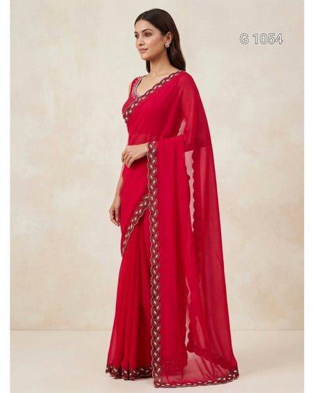 A woman modeling a bright red georgette saree with a matching blouse and dupatta, featuring a decorative border with metallic embroidery. The image is shot against a neutral beige textured backdrop with a style code 'G 1054' in the top right corner.